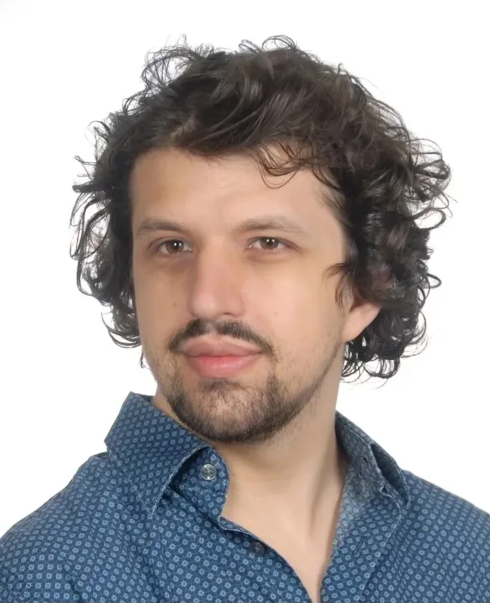a man in a shirt with a cheerful expression, curly hair and a light beard